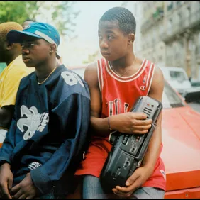 Teenage boys listening to music friom a stereo wearing American style football and basketball tops in Paris