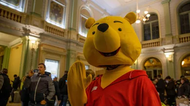 A volunteer is dressing up in Winnie the Pooh costume to
