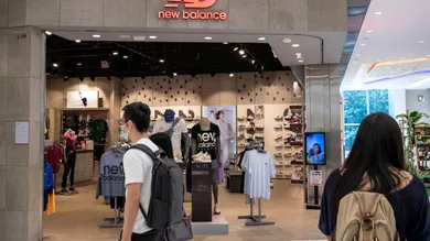 Shoppers walk past the American footwear brand New Balance (