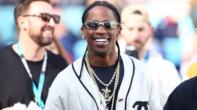 Feb 8, 2026; Santa Clara, CA, USA; Recording artist Travis Scott looks on from the sidelines before Super Bowl LX between the