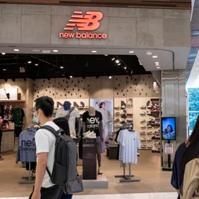 Shoppers walk past the American footwear brand New Balance (