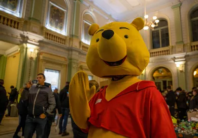 A volunteer is dressing up in Winnie the Pooh costume to