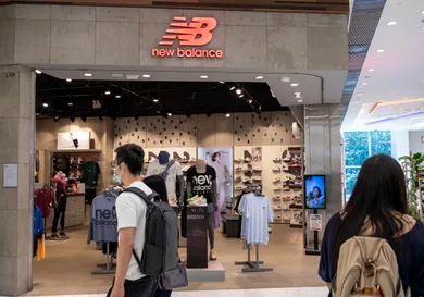 Shoppers walk past the American footwear brand New Balance (